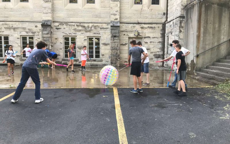 Centenary youth using water guns to move an inflatable ball